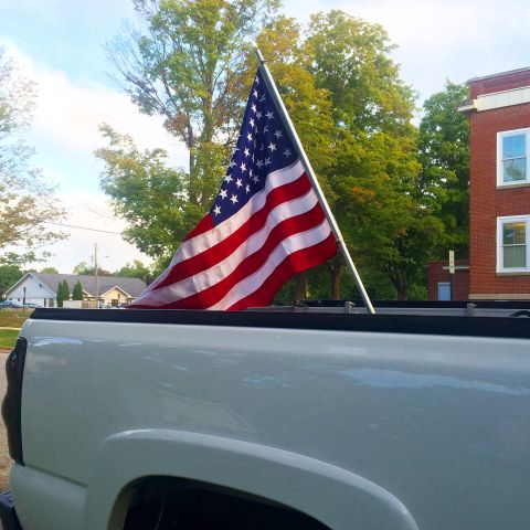 2006 Chevrolet Silverado 2500 - American flag flies from the bed of a white 2006 Chevrolet Silverado 2500 pickup truck.