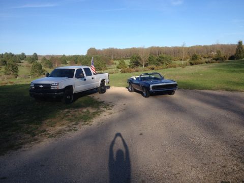2006 Chevrolet Silverado 2500 - A white Chevrolet Silverado 2500 pickup truck and a blue convertible are parked on a gravel road in a rural setting.
