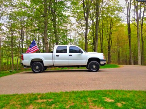 2006 Chevrolet Silverado 2500 - A white 2006 Chevrolet Silverado 2500 is parked on a paved surface with trees in the background.