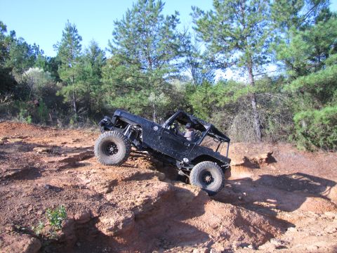 1995 Ford Bronco - Modified off-road vehicle navigating a challenging dirt trail with steep inclines.