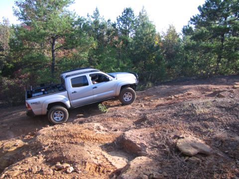 1995 Ford Bronco - Toyota Tacoma TRD Off Road pickup truck navigating a challenging dirt trail.