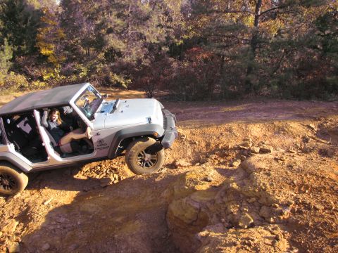 1995 Ford Bronco - A woman sits in a silver Jeep Wrangler as it navigates a rocky off-road path.