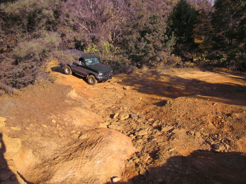 Dark 1995 Ford Bronco driving on a rocky dirt trail