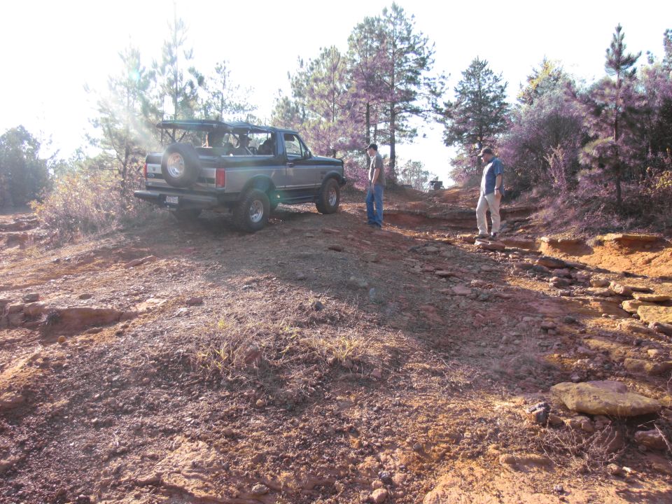 1995 Ford Bronco on a dirt trail with two men standing nearby
