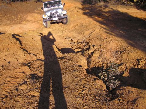 1995 Ford Bronco - A Jeep navigates a challenging off-road path with steep inclines and rocky terrain.