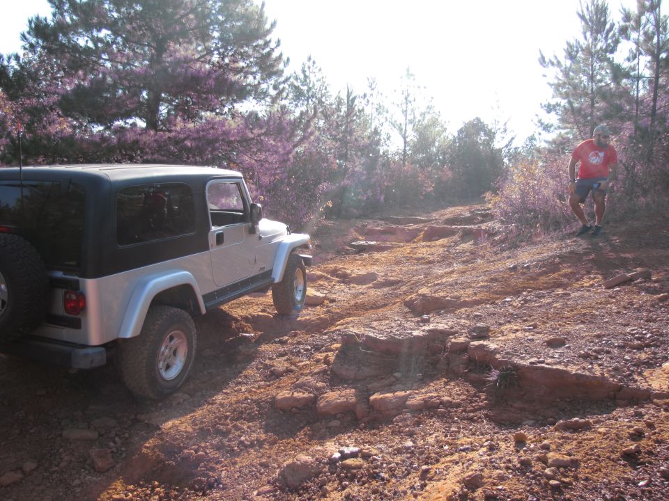 Silver Jeep Wrangler with black top on a rocky, off-road trail