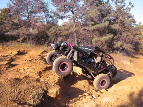 1995 Ford Bronco - A modified Jeep navigates a steep, rocky incline on a sunny day.