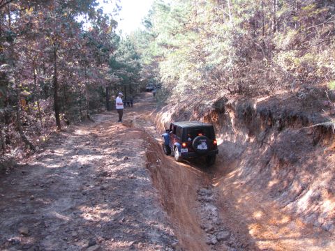 1995 Ford Bronco - A Jeep navigates a challenging off-road trail, with other vehicles and people present.