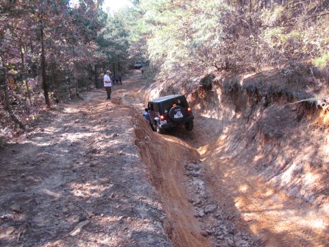1995 Ford Bronco - A Jeep Wrangler navigates a challenging off-road trail with steep inclines and loose dirt.