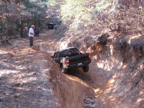 1995 Ford Bronco - Off-road vehicles navigate a challenging trail through a wooded area.