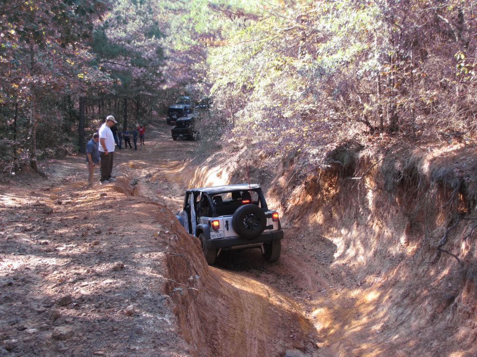 White Jeep Wrangler on a dirt trail, rear view, spare tire mounted