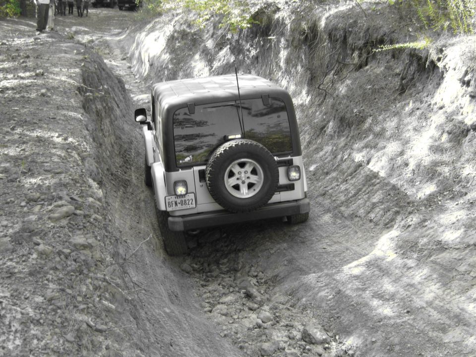 Silver Jeep Wrangler TJ on a dirt trail, rear view