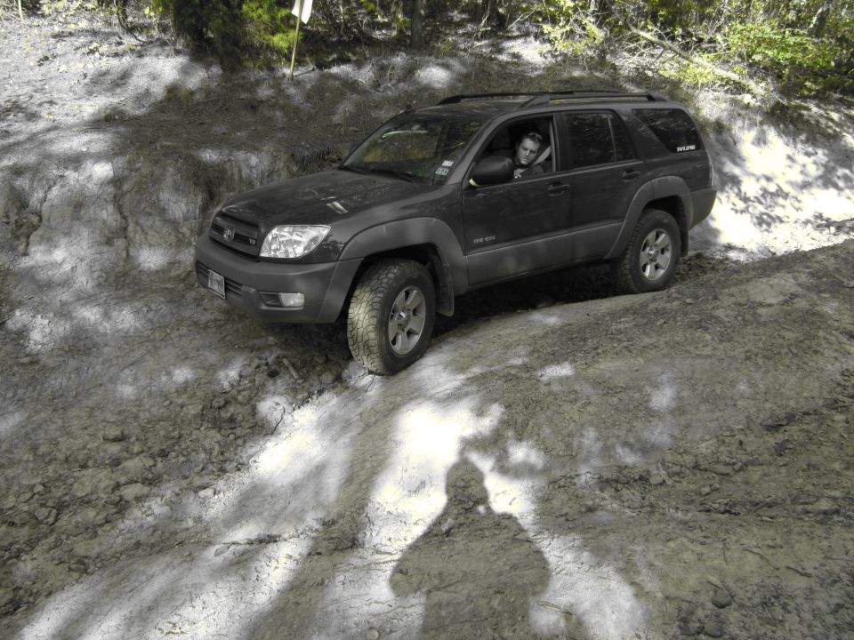 Dark SUV on a dirt trail, driver visible. The vehicle appears to be a Toyota 4Runner