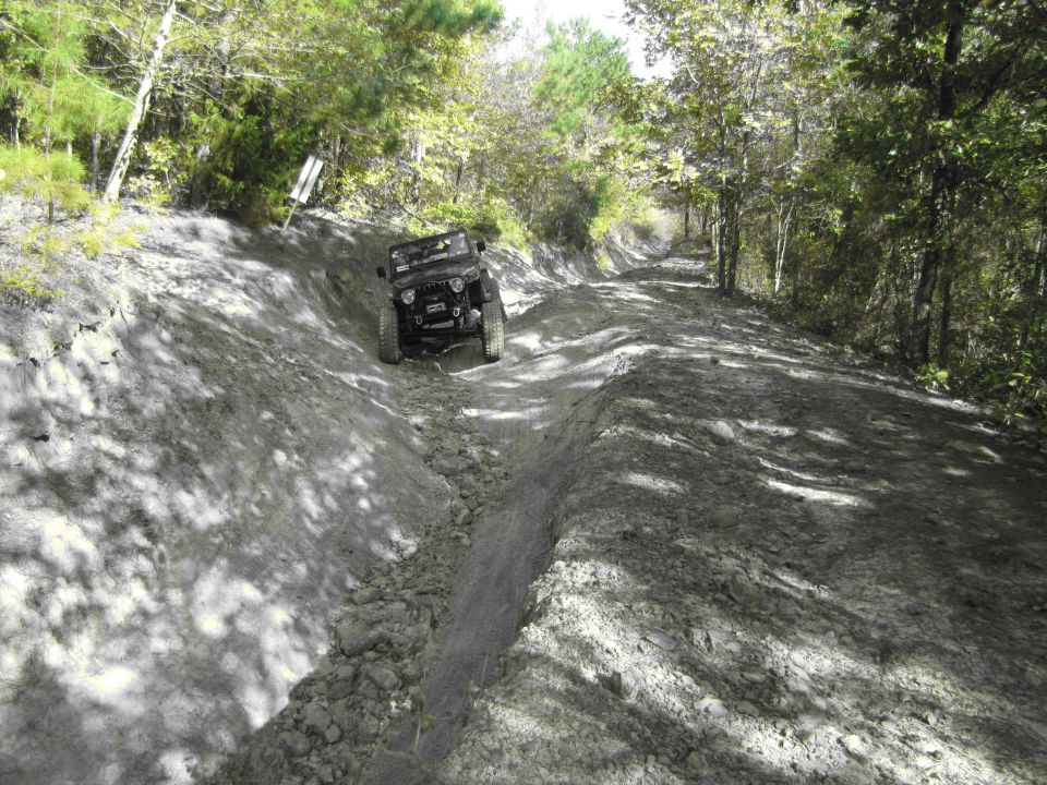Jeep Wrangler driving on a dirt trail with deep ruts
