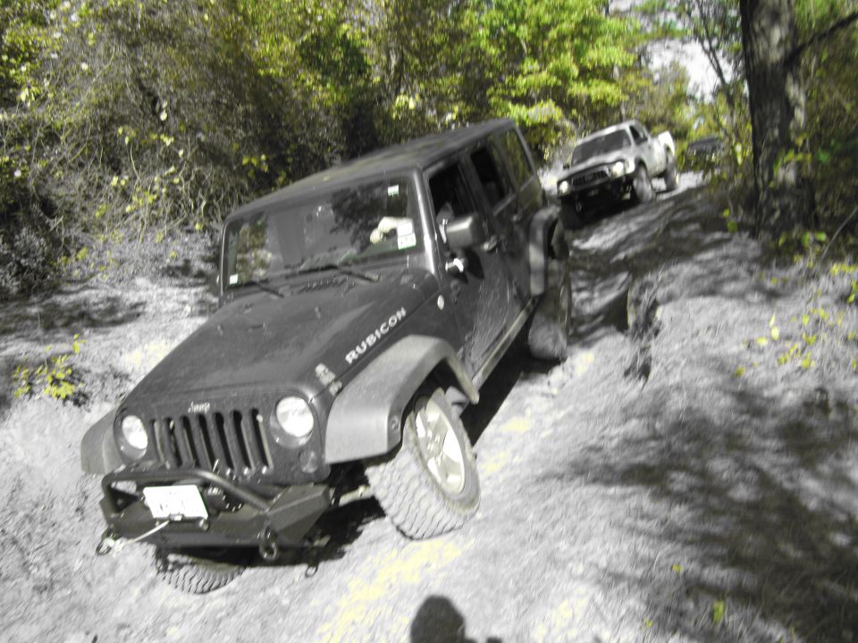 Jeep Wrangler Rubicon driving up a dirt hill with a Toyota Tacoma behind it