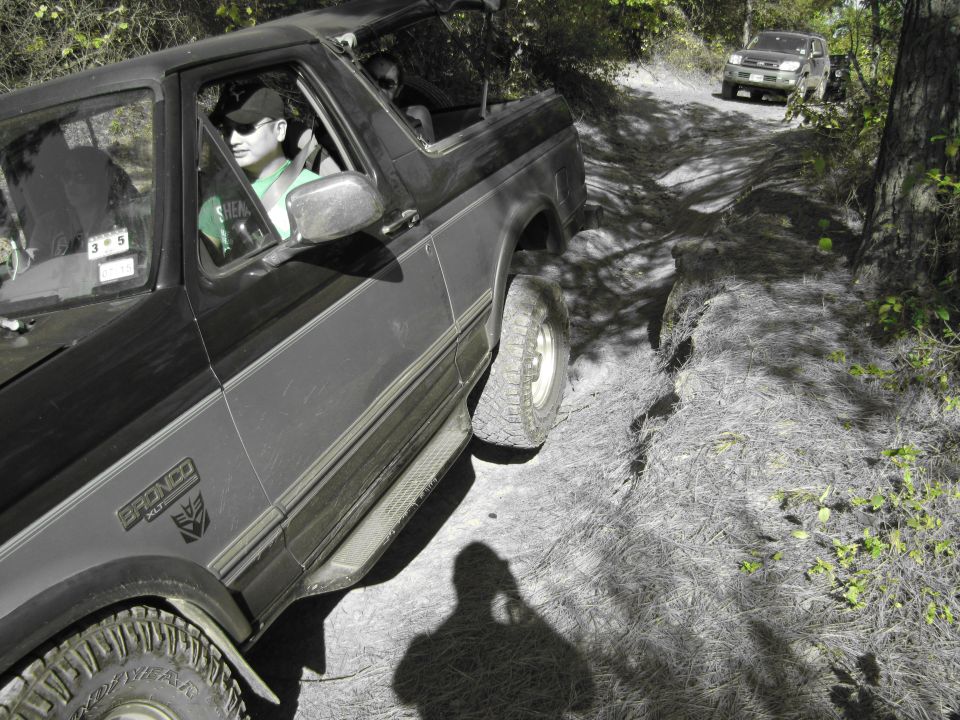 1995 Ford Bronco driving on a dirt trail with another SUV behind it