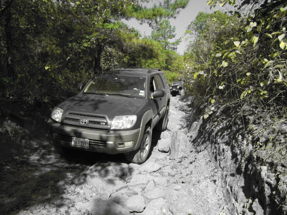 Dark gray Toyota 4Runner on a rocky, off-road trail. Another SUV is visible behind it