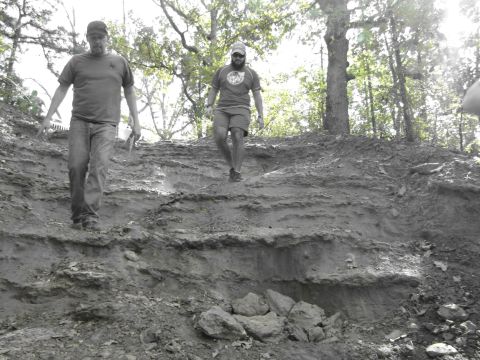 1995 Ford Bronco - Two men navigate a challenging, eroded path in a wooded area.