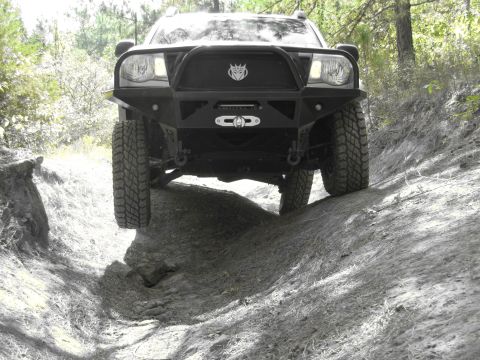 1995 Ford Bronco - An off-road SUV navigates a steep dirt trail, its heavy-duty bumper and winch.