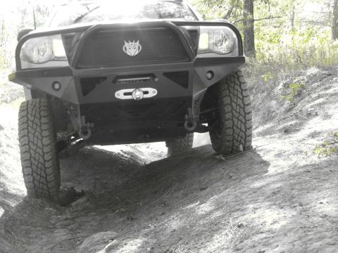 1995 Ford Bronco - Off-road vehicle navigates a dirt track with aggressive tires and custom front bumper.