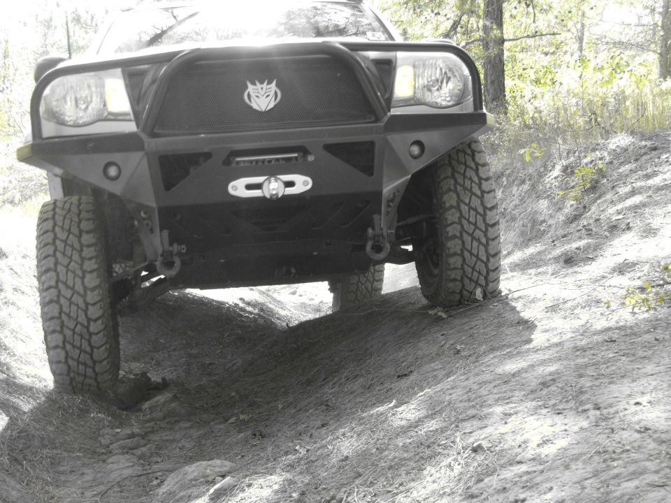 Front view of an off-road vehicle with aftermarket bumper and winch, driving on a dirt path