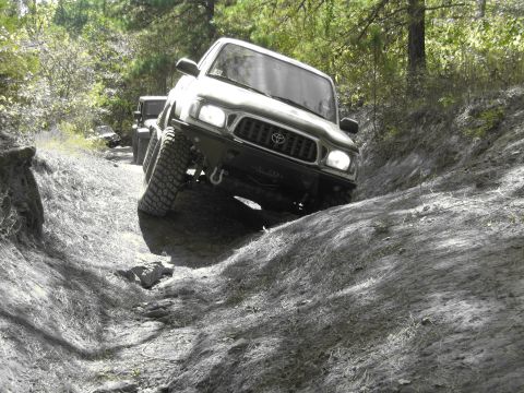 1995 Ford Bronco - A Toyota Tacoma navigates a challenging off-road trail with another vehicle in tow.