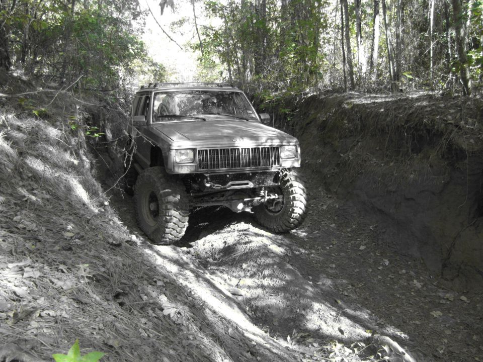 Modified Jeep Cherokee XJ climbing a dirt trail with large tires