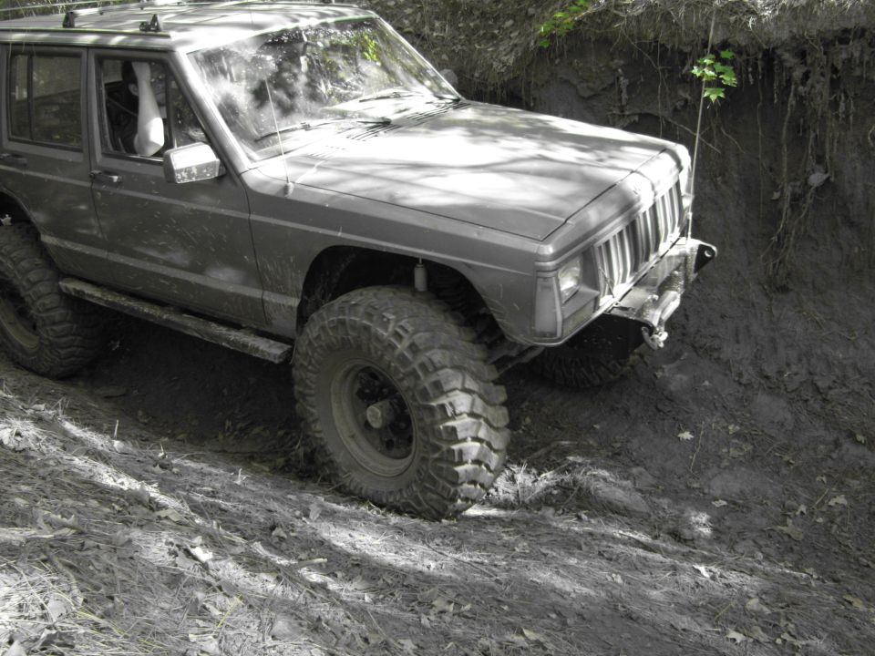 Jeep Cherokee XJ off-roading on a dirt hill with large tires