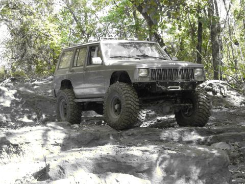 1995 Ford Bronco - Jeep Cherokee XJ navigates a challenging off-road trail with significant suspension articulation.