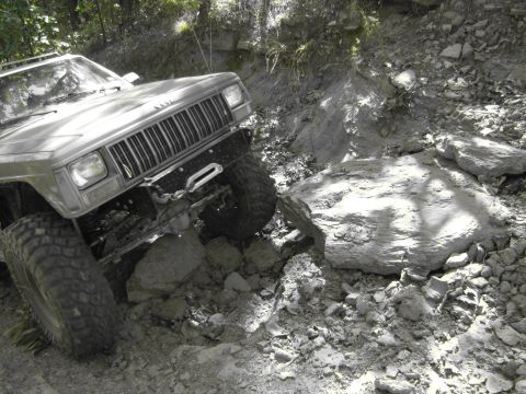 1995 Ford Bronco - Jeep Cherokee XJ tackling a difficult off-road trail with large rocks.