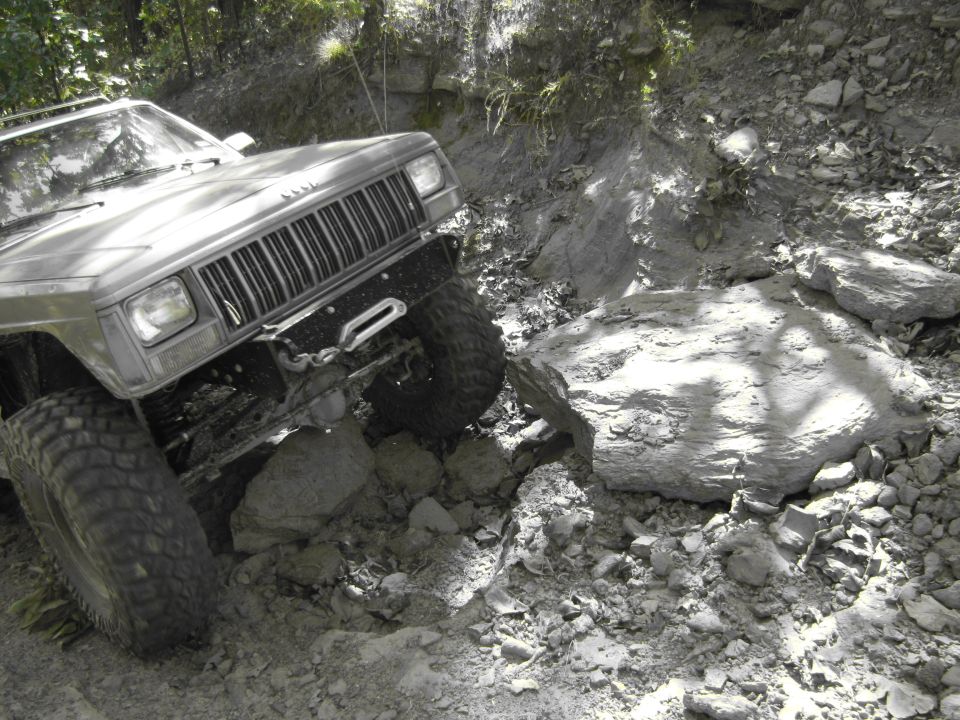 Jeep Cherokee XJ with large tires navigating rocky terrain