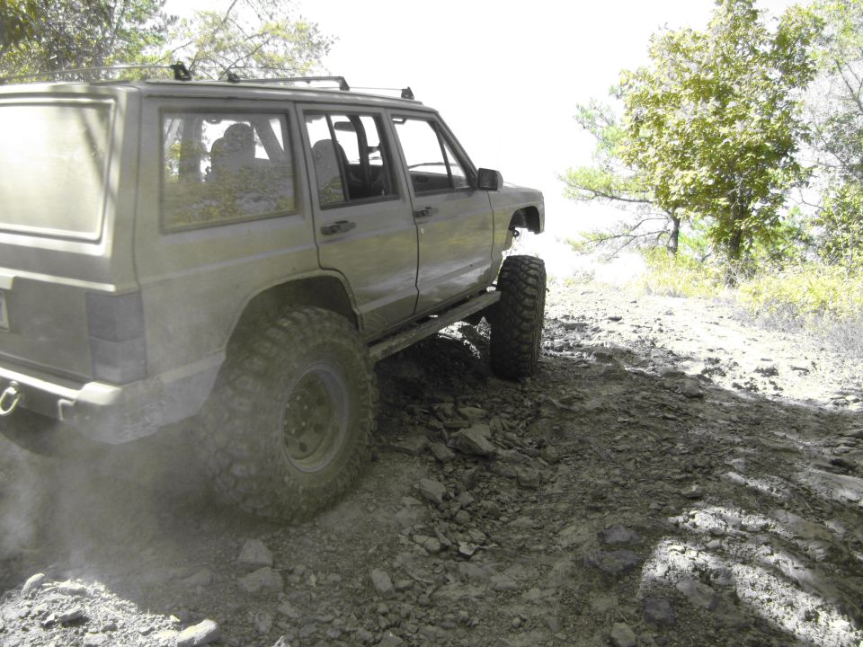 Jeep Cherokee XJ on a rocky trail, kicking up dust