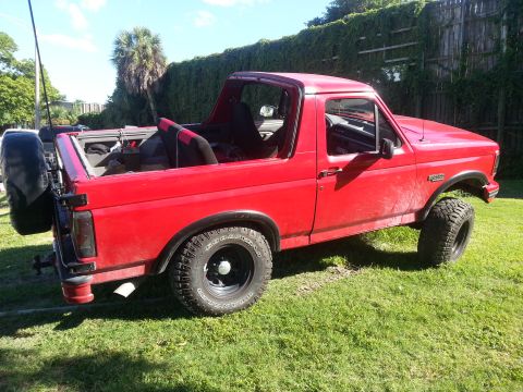 1995 Ford Bronco - This red 1995 Ford Bronco features a removable top and a spare tire mounted on the rear tailgate.