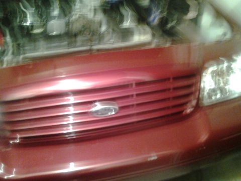 2004 Ford Crown Victoria - Front view of a red 2004 Ford Crown Victoria, showing the grille and headlight detail.