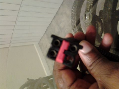 2004 Ford Crown Victoria - Close-up of a hand holding a black electrical connector with a pink locking tab.