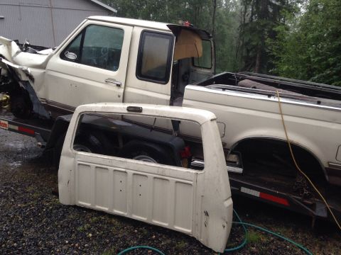 1993 Ford Bronco - A damaged white pickup truck and its detached cab are loaded onto a trailer.