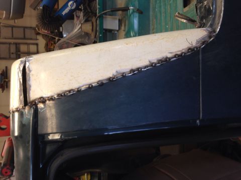 1993 Ford Bronco - Body panel repair work is underway on a dark blue vehicle, showing fresh welds along the seam.