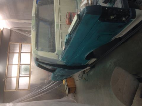 1993 Ford Bronco - A vehicle is undergoing preparation for painting inside a spray booth, with plastic sheeting covering the area.