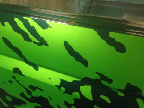 1993 Ford Bronco - A close-up shot of a vehicle's side panel a bright green base coat with black abstract paint designs.
