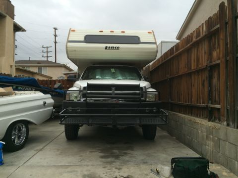 1997 Dodge 3500 - A white Dodge Ram truck with a camper shell is parked in a driveway next to a boat and a white car.