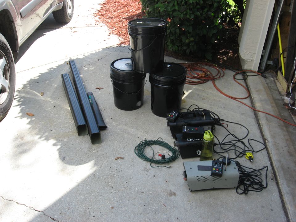 Side view of a dark-colored SUV with black downspouts, buckets, and fog machines on concrete