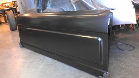 1989 Ford Bronco - A new black tailgate is shown in a workshop setting, awaiting installation.