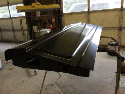 1989 Ford Bronco - A black tailgate is mounted on a stand, likely undergoing preparation or repair in a garage setting.