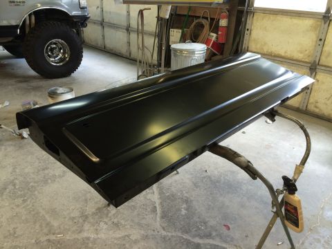 1989 Ford Bronco - Black tailgate on a stand in a garage, with a silver Ford truck in the background.