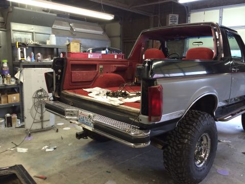 1989 Ford Bronco - This lifted Ford Bronco, with a two-tone paint job and red interior, is viewed from the rear in a garage setting.