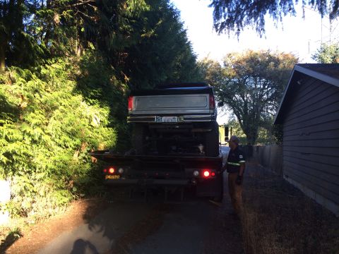 1989 Ford Bronco - A tow truck is hauling a Ford F-Series truck, possibly from the 1980s, down a residential street.