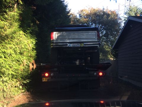 1989 Ford Bronco - Rear view of a lifted pickup truck on a tow truck, with a silver tailgate and chrome bumper visible.