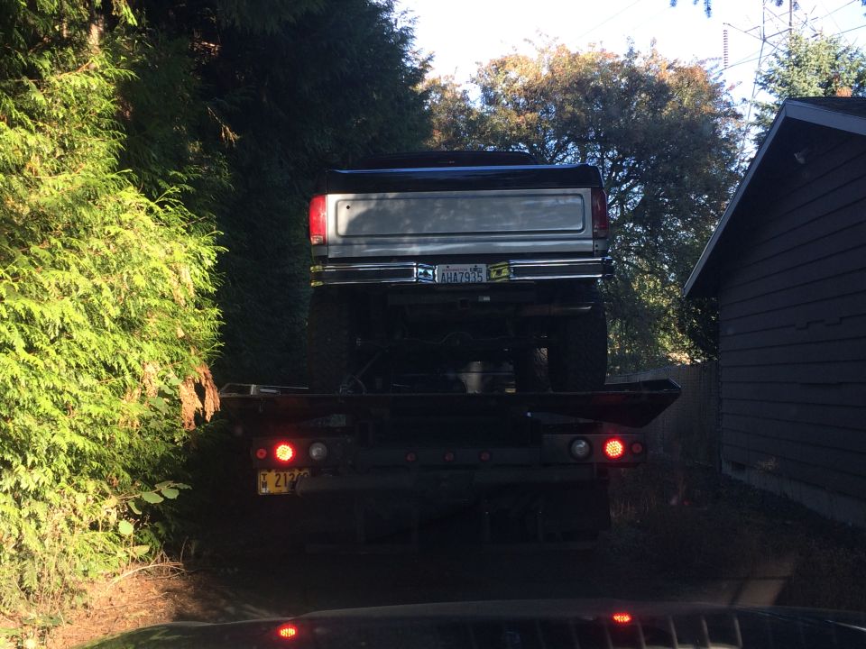 Silver tailgate and chrome bumper on a lifted pickup truck being towed