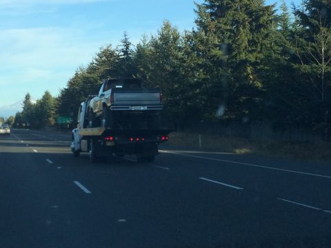 1989 Ford Bronco - A 1987 Ford F-150 pickup truck is transported on a flatbed tow truck along a highway.