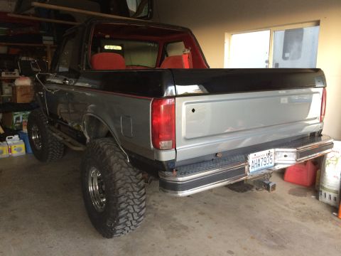 1989 Ford Bronco - Rear view of a lifted Ford Bronco with a two-tone paint job and aftermarket wheels.